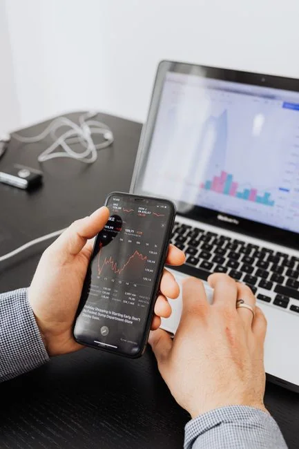 Des mains utilisent une tablette à côté d’un ordinateur portable, dans un bureau à domicile, pour illustrer la navigation en ligne.